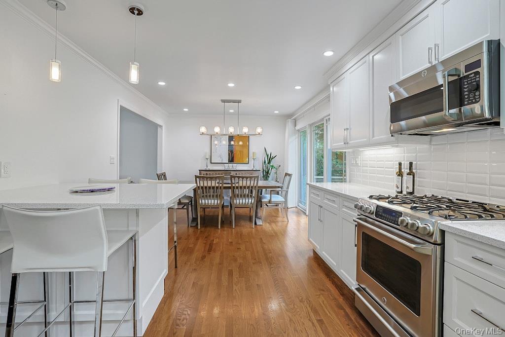 305 Stratton Road New Rochelle, NY 10804 - Photo 12 of 32 a kitchen with stainless steel appliances a stove a sink a microwave a stove and white cabinets with wooden floor