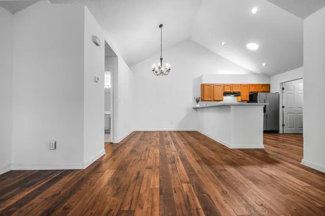 a view of a kitchen with wooden floor and a hallway