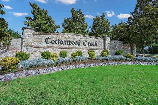a sign of golf club on a wall under a tree