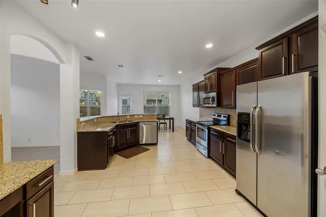 a large kitchen with stainless steel appliances kitchen island granite countertop a refrigerator and a sink