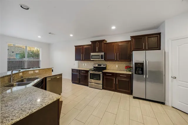 a kitchen with stainless steel appliances granite countertop a sink dishwasher stove top oven and refrigerator