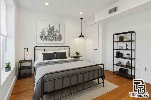 a bedroom with a bed paintings on the wall and dresser
