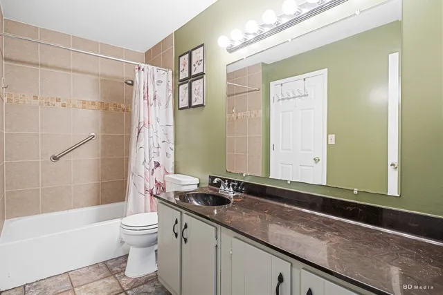 a bathroom with a granite countertop sink a toilet and shower