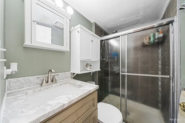 a bathroom with a granite countertop sink toilet and shower