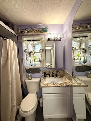 a bathroom with a granite countertop toilet a sink and a mirror
