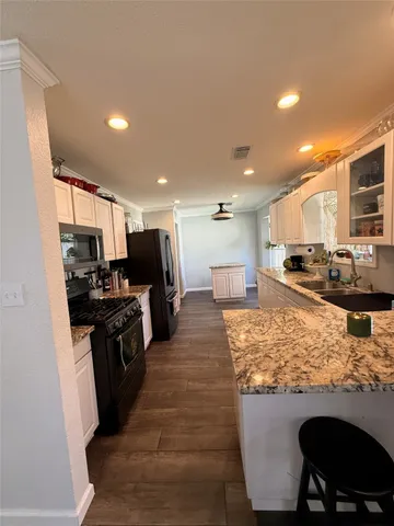 a kitchen with stainless steel appliances granite countertop a stove top oven a sink a dining table and chairs