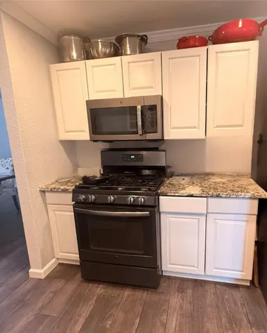 a kitchen with granite countertop wooden cabinets and a stove top oven