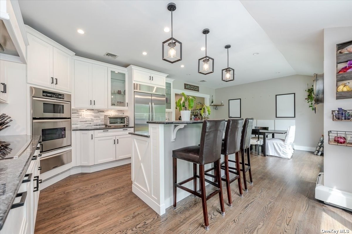a kitchen with stainless steel appliances a dining table chairs stove and cabinets