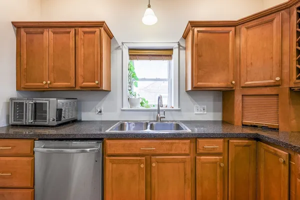 a kitchen with stainless steel appliances granite countertop a sink a refrigerator cabinets and a window