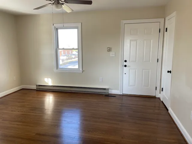 a view of an empty room with wooden floor and a window