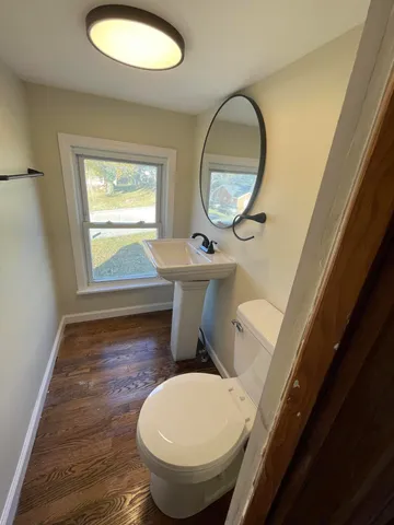 a bathroom with a toilet mirror a sink and a window