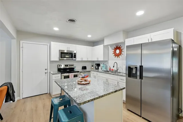 a kitchen with stainless steel appliances granite countertop a refrigerator a stove and a sink with wooden floor