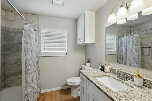 a bathroom with a granite countertop sink a toilet and a mirror