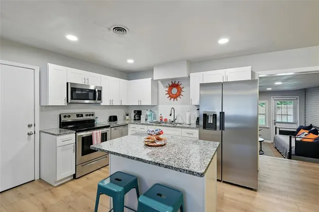 a kitchen with granite countertop stainless steel appliances a stove refrigerator sink and cabinets