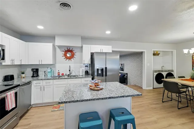 a kitchen with granite countertop kitchen island stainless steel appliances a sink and refrigerator