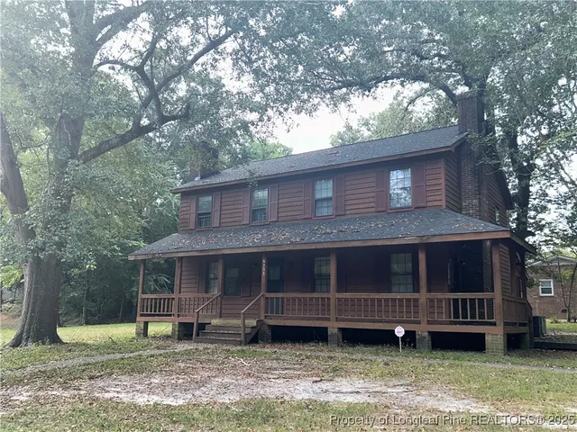 a view of a house with a yard and large tree