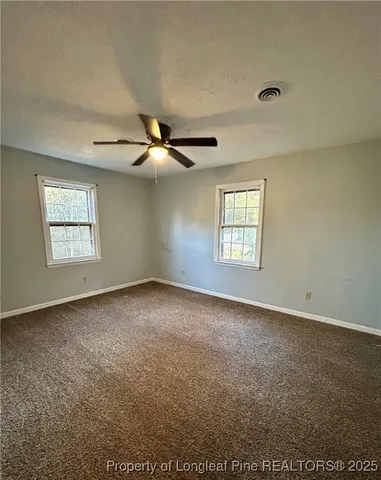 an empty room with windows and fan