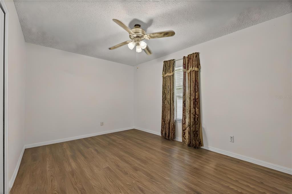 8453 Apple Orchard Road Spring Hill, FL 34608 - Photo 20 of 66 an empty room with wooden floor chandelier fan and closet area