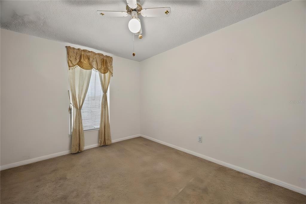 8453 Apple Orchard Road Spring Hill, FL 34608 - Photo 22 of 66 an empty room with a ceiling fan and a window