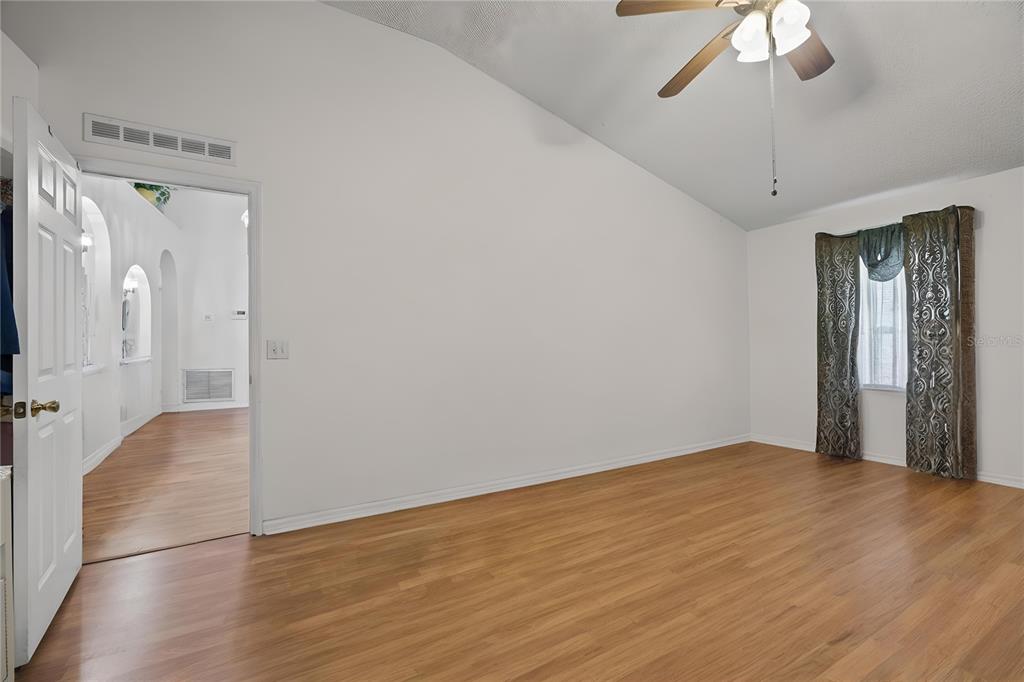 8453 Apple Orchard Road Spring Hill, FL 34608 - Photo 28 of 66 a view of an empty room with wooden floor and a ceiling fan