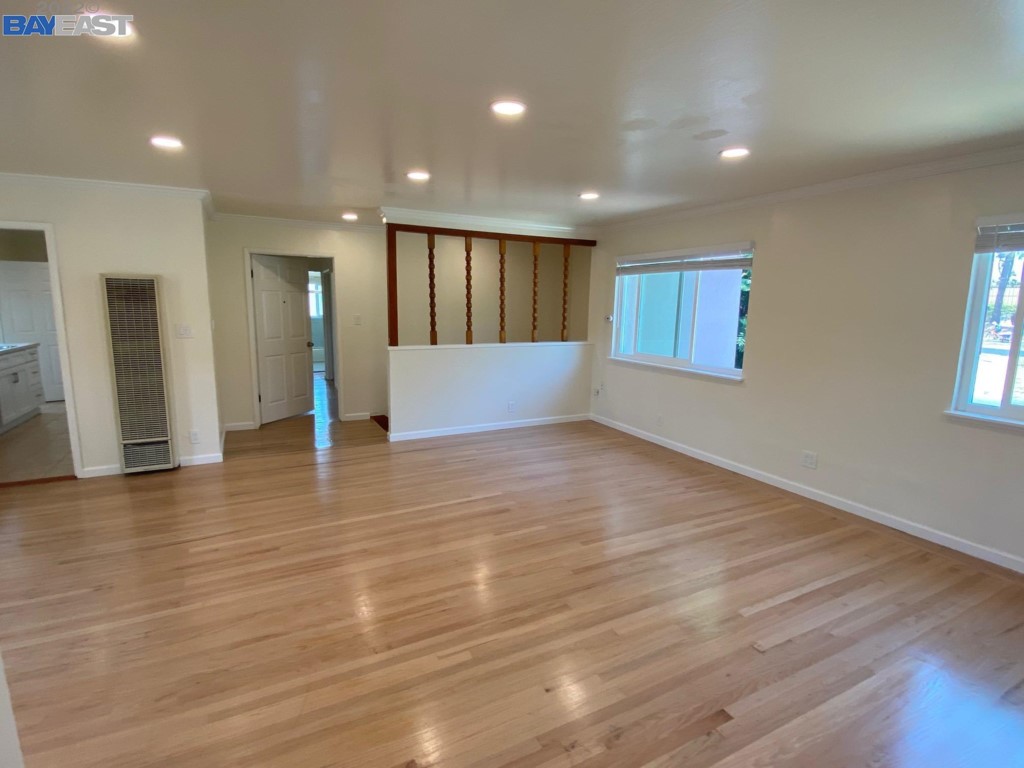a view of an empty room with wooden floor and windows