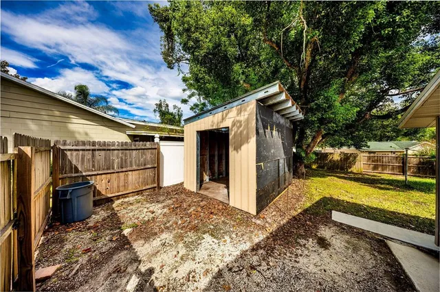 a view of a house with a large tree and wooden fence