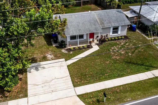 a view of a house with a small yard and large tree