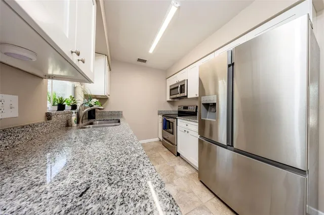 a kitchen with stainless steel appliances granite countertop a refrigerator and a sink