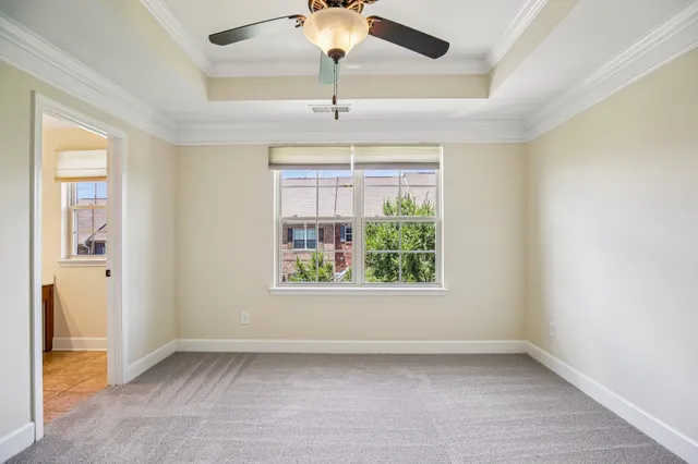 an empty room with windows and chandelier fan