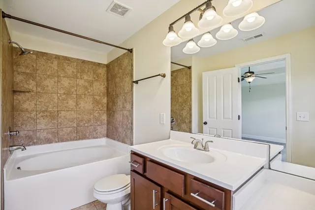 a bathroom with a sink a toilet a mirror a bathtub and shower