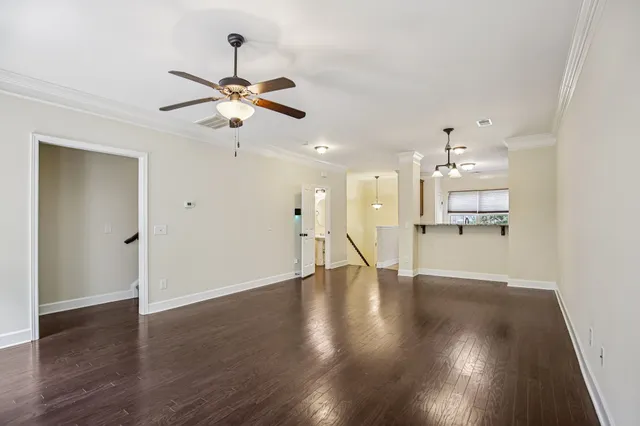 a view of an empty room with wooden floor and a ceiling fan