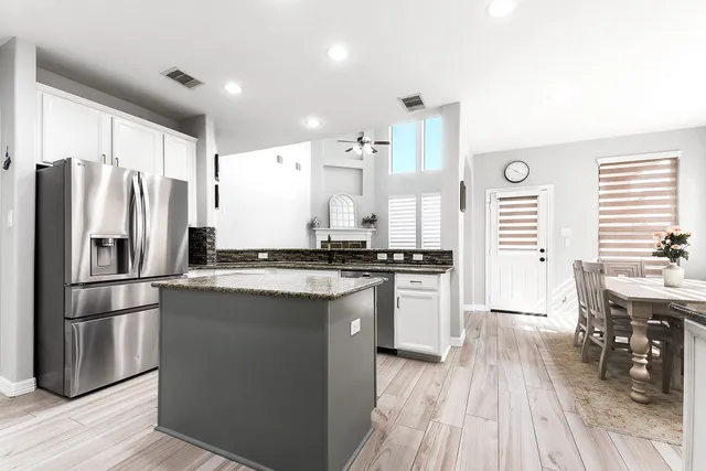 a kitchen with stainless steel appliances a refrigerator a sink dishwasher a stove and white countertops with wooden floor