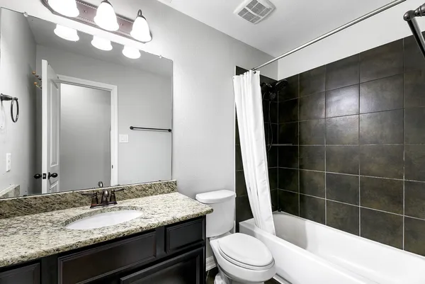 a bathroom with a granite countertop sink toilet mirror and bathtub