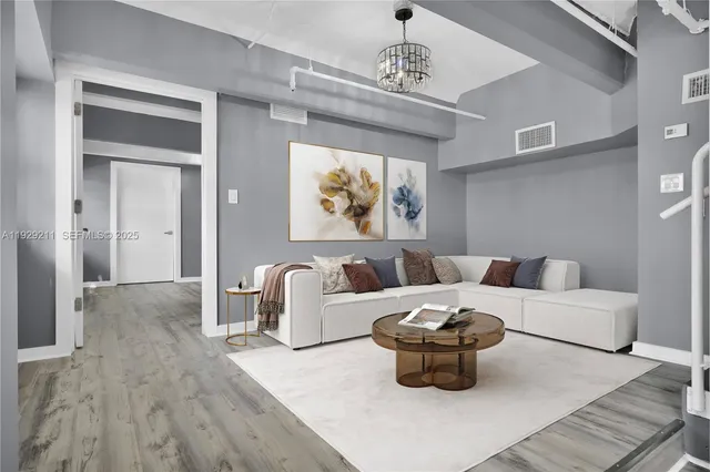 a living room with furniture a chandelier and wooden floor