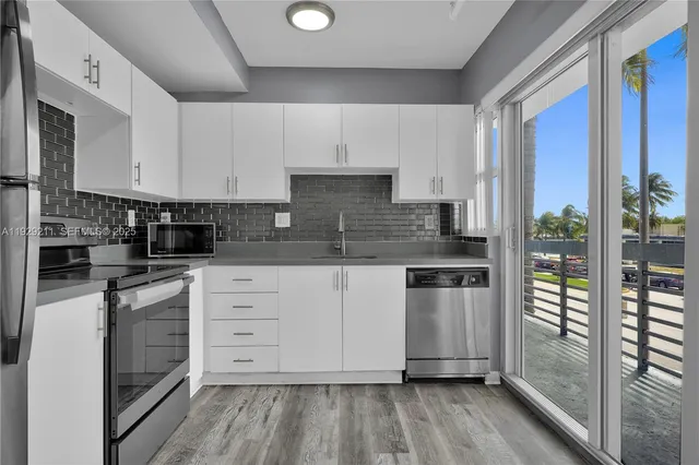 a kitchen with stainless steel appliances granite countertop a stove a sink and white cabinets