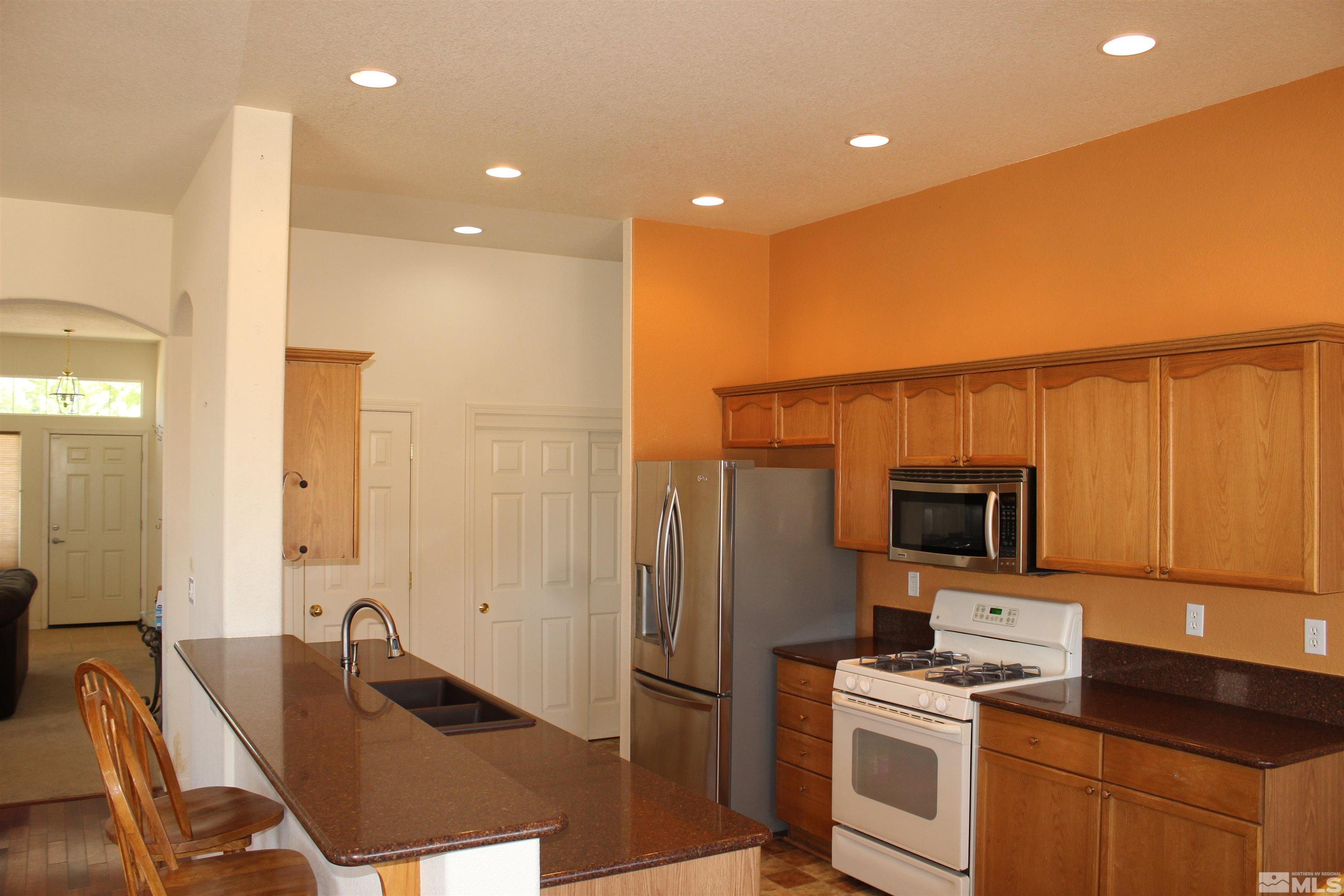 9533 Steep Climb Court Reno, NV 89521 - Photo 7 of 15 a kitchen with stainless steel appliances granite countertop a refrigerator a stove and a sink with wooden floor