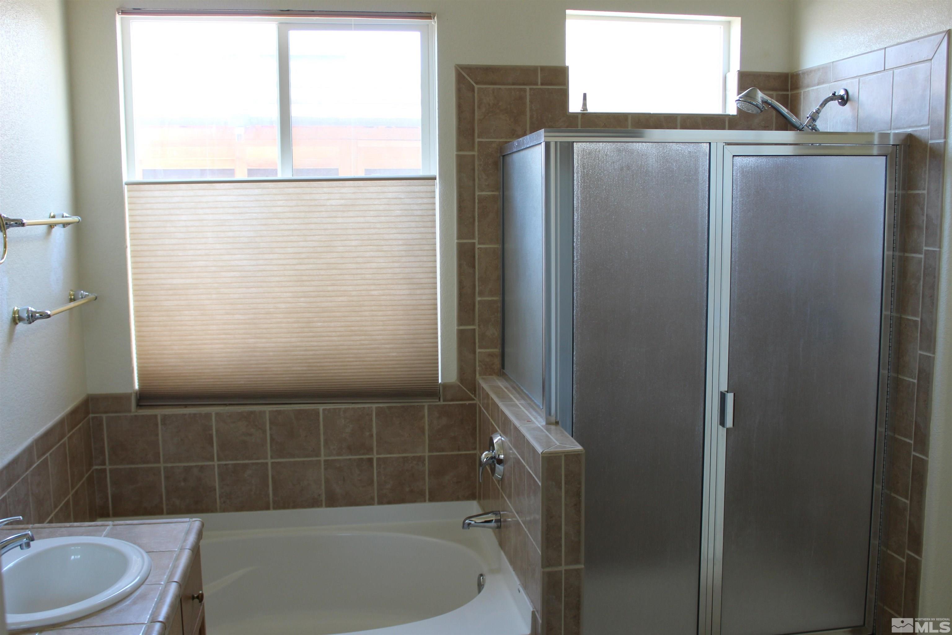 9533 Steep Climb Court Reno, NV 89521 - Photo 9 of 15 a bathroom with a bathtub a window a toilet and a shower