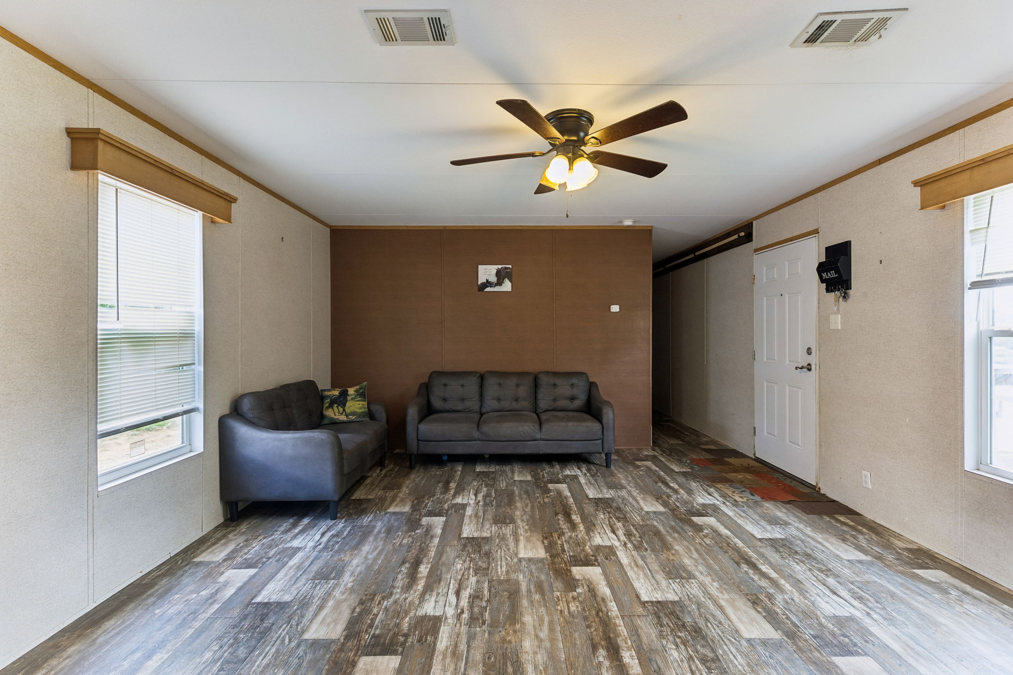 253 North County Line Road, Unit C Elgin, TX 78621 - Photo 7 of 39 A welcoming interior offers durable plank flooring and a functional ceiling fan.