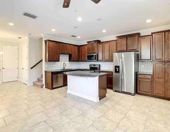 a kitchen with granite countertop a refrigerator and a stove top oven