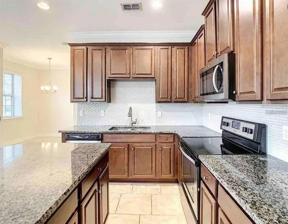 a kitchen with stainless steel appliances granite countertop a stove a sink and a microwave