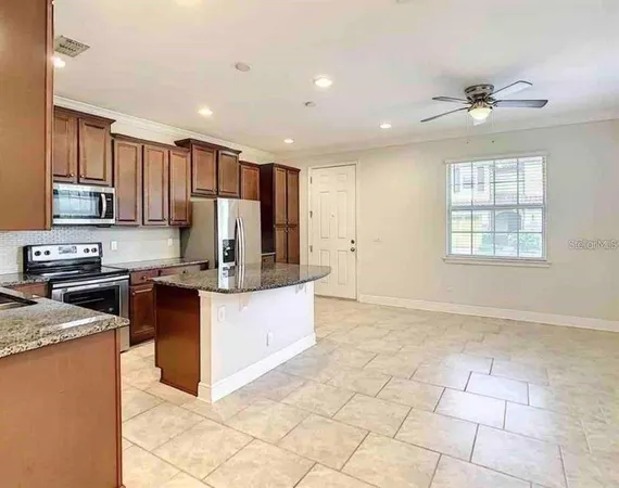 a kitchen with stainless steel appliances granite countertop a stove top oven a sink a counter top space cabinets and a window