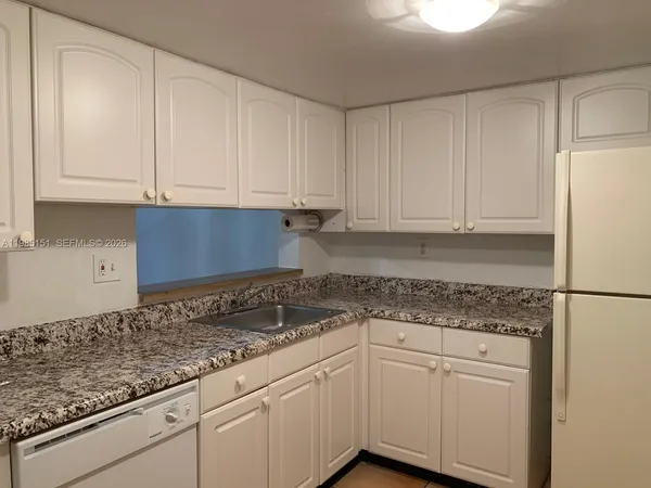 a kitchen with granite countertop white cabinets and white appliances