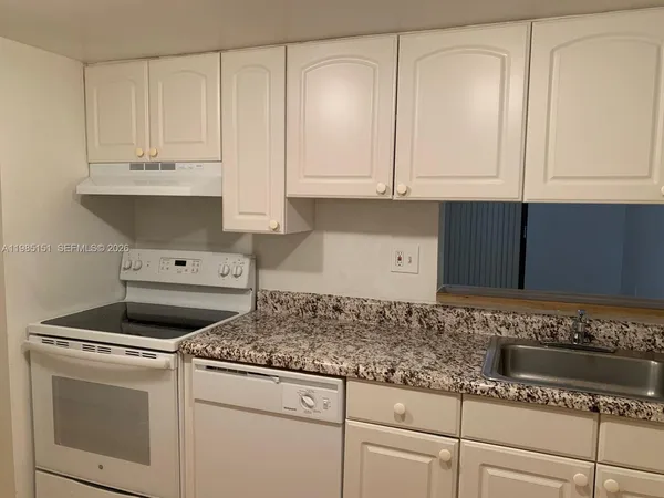 a kitchen with granite countertop white cabinets and white appliances
