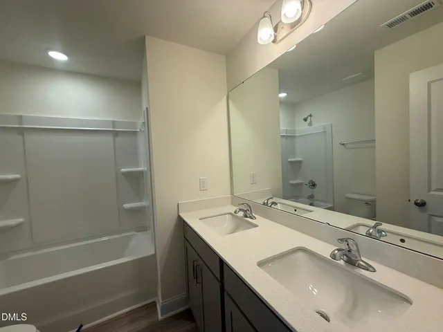 a bathroom with a tub sink double vanity and shower