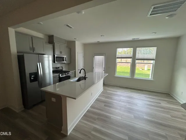 a kitchen with stainless steel appliances granite countertop a refrigerator a sink a stove and wooden floor