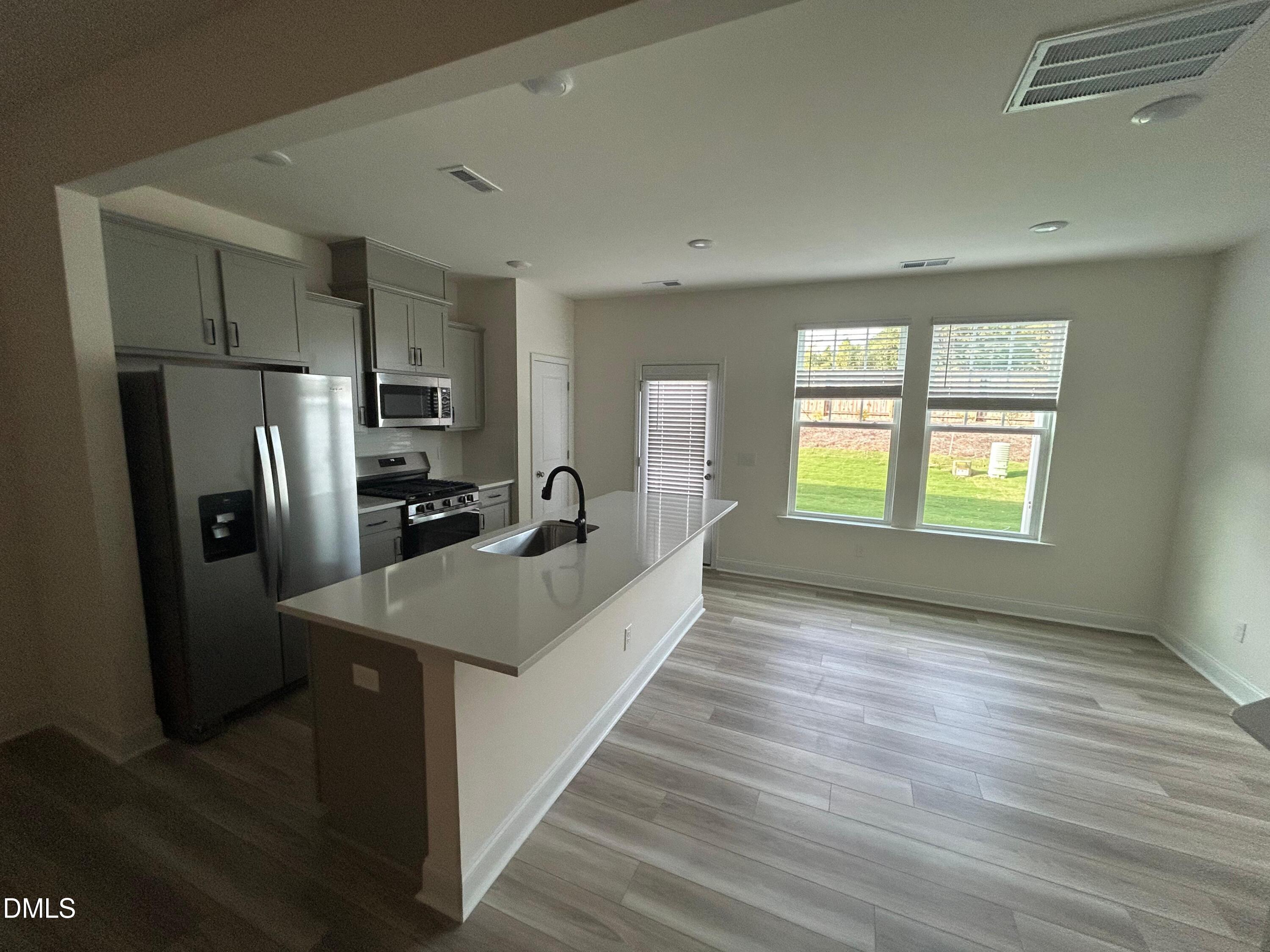 66 Bloodroot Street Angier, NC 27501 - Photo 3 of 16 a kitchen with stainless steel appliances granite countertop a refrigerator a sink a stove and wooden floor