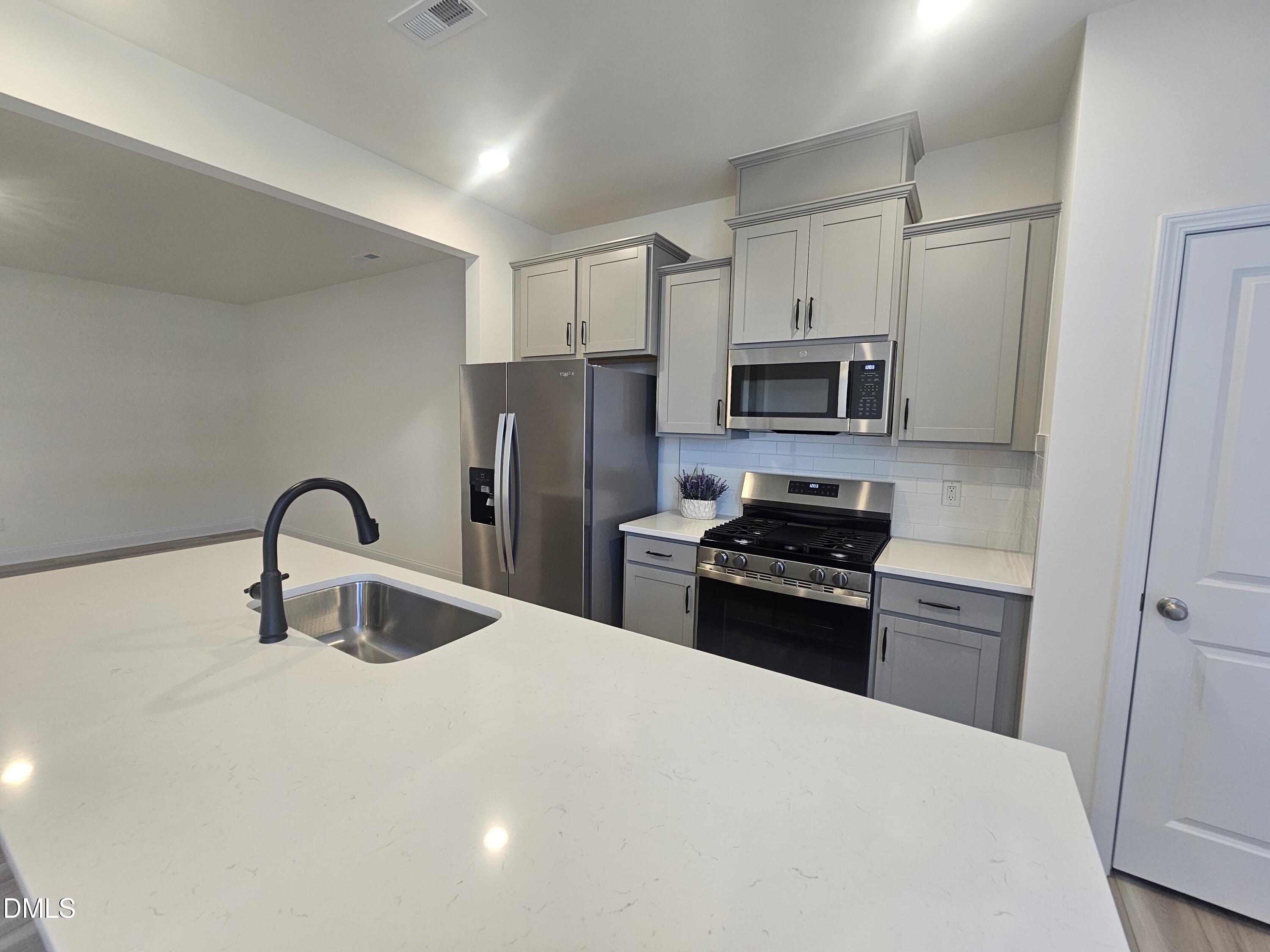66 Bloodroot Street Angier, NC 27501 - Photo 6 of 16 a kitchen with refrigerator a microwave and cabinets