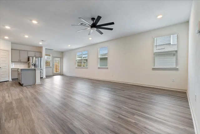 a view of an empty room with a window and wooden floor