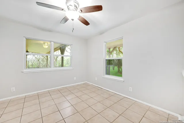 an empty room with windows and fan