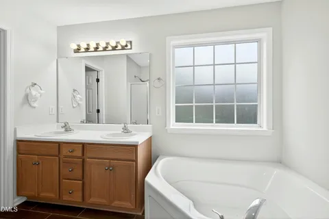 a bathroom with a tub a sink and a window